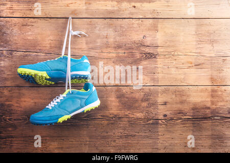 Paar Sportschuhe hängen an einem Nagel auf einem Holzzaun-Hintergrund Stockfoto