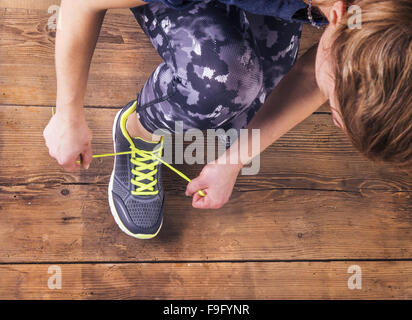 Nicht erkennbare junge Läufer ihre Schnürsenkel zu binden. Studio auf Holzboden Hintergrund gedreht. Stockfoto