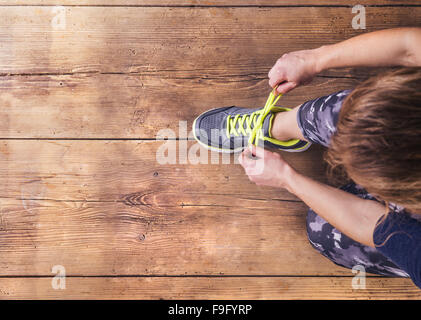 Nicht erkennbare junge Läufer ihre Schnürsenkel zu binden. Studio auf Holzboden Hintergrund gedreht. Stockfoto