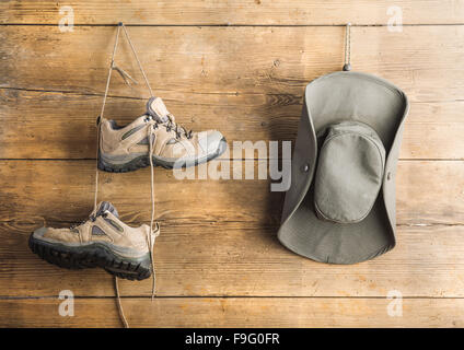 Wanderschuhe und Hut hängen an einem Holzzaun-Hintergrund Stockfoto