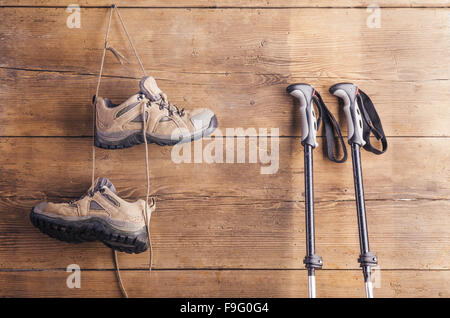 Nordic walking-Stöcken und Wanderschuhe hängen an einem Holzzaun-Hintergrund Stockfoto