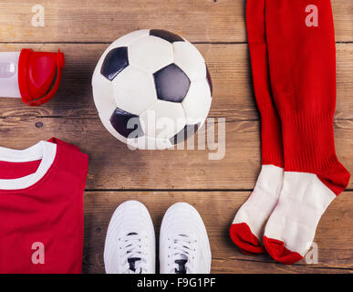 Verschiedene Fußball-Sachen aufgereiht auf einem Holzboden-Hintergrund Stockfoto