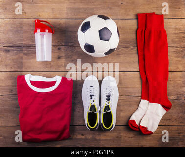 Verschiedene Fußball-Sachen aufgereiht auf einem Holzboden-Hintergrund Stockfoto