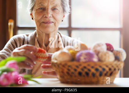 Schöne ältere Frau mit Ostereier und Tulpen. Stockfoto