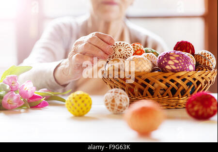 Nicht erkennbare senior Frau mit Ostereiern und Tulpen. Stockfoto