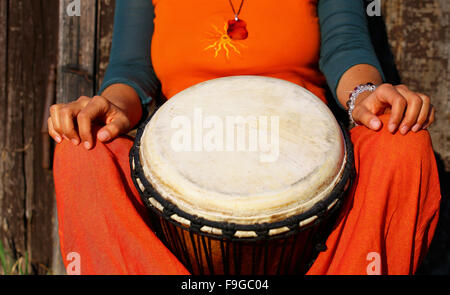 Junge Dame Schlagzeuger mit ihrer Djembe-Trommel auf rustikale Holztür Hintergrund. Stockfoto