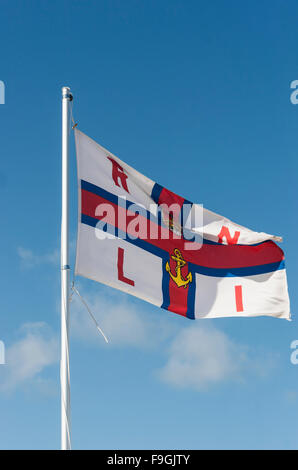 Flagge der Royal National Lifeboat Institution auf eine Fahnenstange vor einem blauen Himmel fliegen Stockfoto