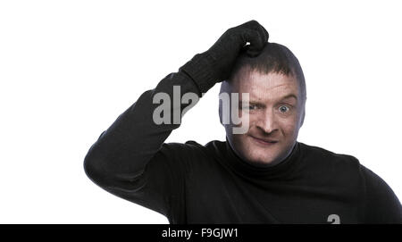 Dieb in Balaclava lustige Grimassen, in schwarz gekleidet. Studio auf weißem Hintergrund gedreht. Stockfoto