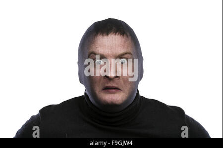 Dieb in Balaclava lustige Grimassen, in schwarz gekleidet. Studio auf weißem Hintergrund gedreht. Stockfoto