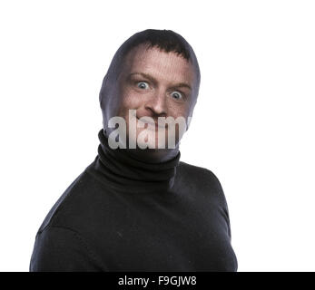 Dieb in Balaclava lustige Grimassen, in schwarz gekleidet. Studio auf weißem Hintergrund gedreht. Stockfoto