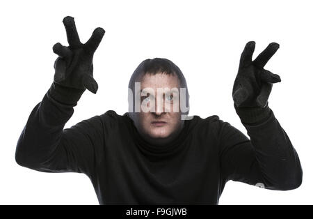 Dieb in Balaclava lustige Grimassen, in schwarz gekleidet. Studio auf weißem Hintergrund gedreht. Stockfoto