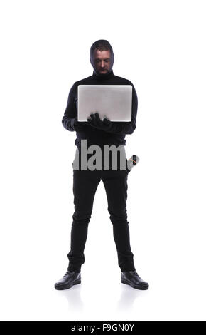 Schwarz gekleidete Dieb in Aktion Informationen mit Sturmhaube auf seinem Gesicht zu stehlen. Studio auf weißem Hintergrund gedreht. Stockfoto