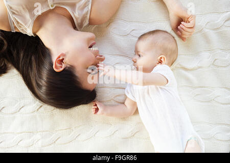 Niedliche kleine Baby-Mädchen und ihre Mutter auf eine gestrickte Decke liegen. Stockfoto