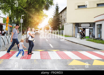 Junge Familie mit zwei jungen in der Stadt zu Fuß auf einem Zebrastreifen Stockfoto