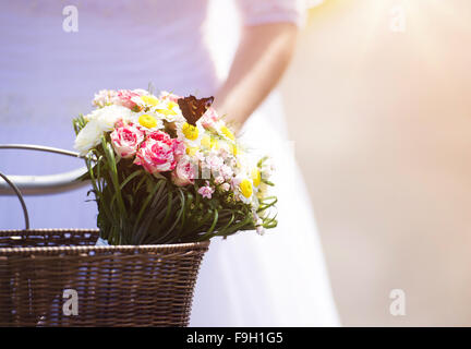 Unkenntlich schöne junge Braut außerhalb auf dem Fahrrad in den Sonnenuntergang Stockfoto