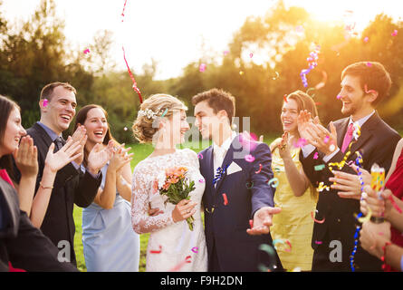 In voller Länge Portrait von Brautpaar und ihre Freunde bei der Hochzeit mit Konfetti in sonnigen Grünanlage geduscht Stockfoto