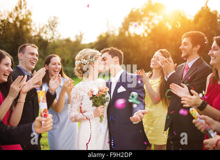 In voller Länge Portrait von Brautpaar und ihre Freunde bei der Hochzeit mit Konfetti in sonnigen Grünanlage geduscht Stockfoto