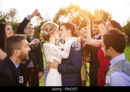 In voller Länge Portrait von Brautpaar und ihre Freunde bei der Hochzeit mit Konfetti in sonnigen Grünanlage geduscht Stockfoto