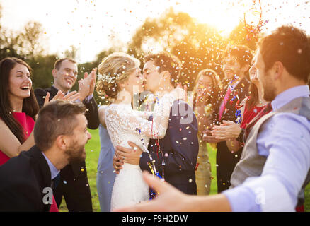 In voller Länge Portrait von Brautpaar und ihre Freunde bei der Hochzeit mit Konfetti in sonnigen Grünanlage geduscht Stockfoto