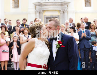 Braut und Bräutigam vor der Kirche mit ihren Freunden und Familie Stockfoto