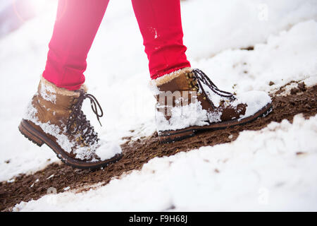 Nicht erkennbare Frau in roten Hosen und Stiefel draußen im Schnee. Stockfoto