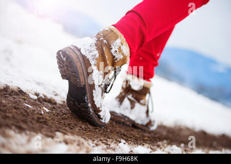 Nicht erkennbare Frau in roten Hosen und Stiefel draußen im Schnee. Stockfoto