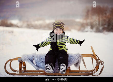 Niedliche kleine Junge auf Schlitten Spaß draußen im Schnee im Winter. Stockfoto