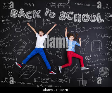 Netten jungen und Mädchen lernen spielerisch im Frot an einer großen Tafel. Studio auf schwarzem Hintergrund gedreht. Stockfoto