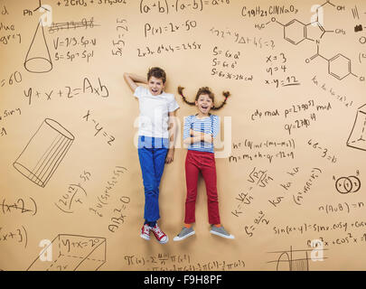 Netten jungen und Mädchen lernen spielerisch im Frot an einer großen Tafel. Studio auf Beige Hintergrund gedreht. Stockfoto