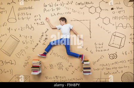 Niedliche kleine Junge lernen spielerisch im Frot an einer großen Tafel. Studio auf Beige Hintergrund gedreht. Stockfoto