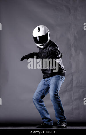 Autofahrer mit einem Helm, Lederjacke und Jeans auf Grunge Hintergrund mit grellem Licht Stockfoto