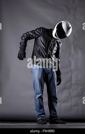 Autofahrer mit einem Helm, Lederjacke und Jeans auf Grunge Hintergrund mit grellem Licht Stockfoto