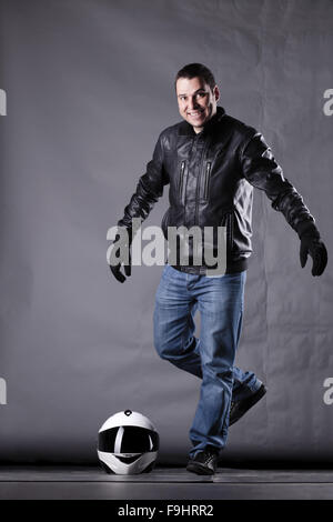 Autofahrer mit einem Helm, Lederjacke und Jeans auf Grunge Hintergrund mit grellem Licht Stockfoto