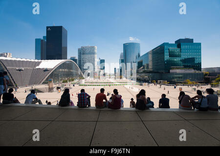 Leute sitzen mit herrlichem Blick auf die Umgebung von La Defense aus oberen Stufen der Grande Arche, ein beliebter Ort zum entspannen und Mittagessen Stockfoto