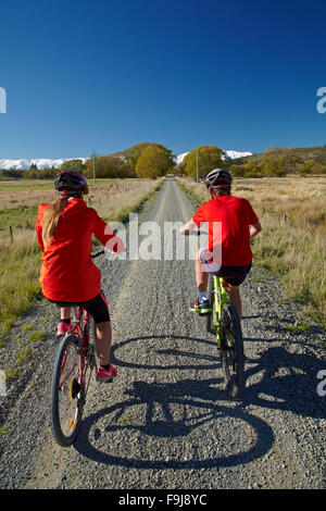 Radfahrer auf Otago Central Rail Trail im Ida-Tal und Schnee auf Ida Range, Central Otago, Südinsel, Neuseeland Stockfoto