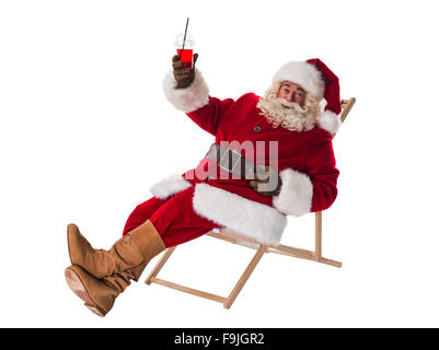 Weihnachtsmann auf Liegestuhl sitzen und trinken cocktail voller Länge Portrait isoliert auf weißem Hintergrund Stockfoto