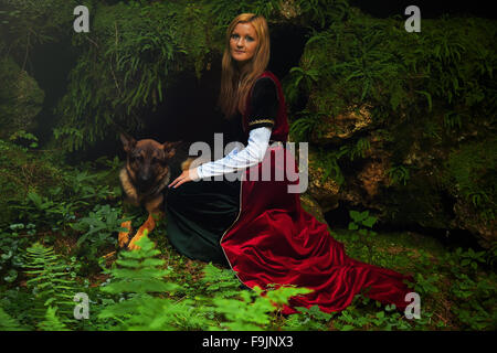 Eine schöne Frau Fee mit langen blonden Haaren in einem historischen Gewand, mit Hund Stockfoto