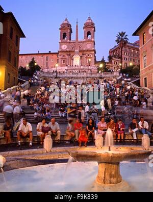 Touristen sitzen auf der spanischen Treppe mit einem Brunnen im Vordergrund bei Nacht, Rome, Italy, Europe. Stockfoto