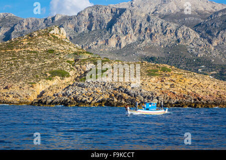 Kleine weiße und blaue Fischerboot, mit zwei Fischer, blaues Meer und felsigen Küste Stockfoto