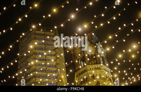 Berlin, Deutschland. 16. Dezember 2015. Lichterkette auf dem Weihnachtsmarkt am Breitscheidplatz vor der Kaiser-Wilhlem-Gedächtniskirche in Berlin, Deutschland, 16. Dezember 2015 leuchtet. Das ursprüngliche Gebäude entstand ab 1891-95 nach Plänen von Franz Schwechten. Nach dem zweiten Weltkrieg wurden die Ruinen (R) als ein Anti-Kriegs-Denkmal geschützt. Ein neuer Turm wurde nach Plänen von Architekt Egon Eiermann errichtet. Foto: PAUL ZINKEN/Dpa/Alamy Live News Stockfoto