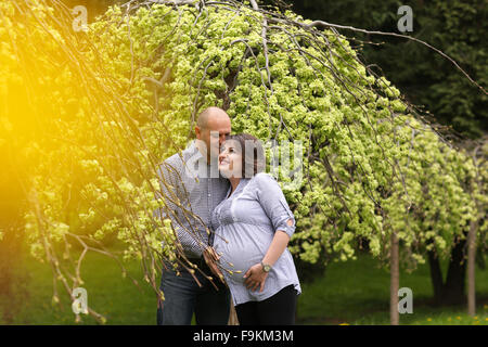 Glücklich und junge schwangere paar umarmen in der Natur Stockfoto