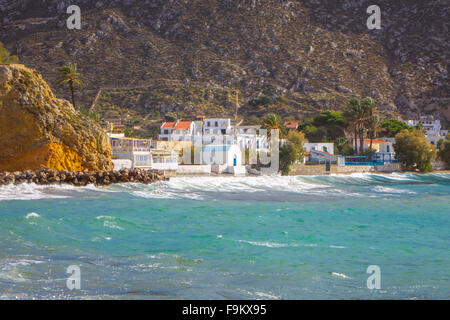 Weiße Wellen brechen sich am Strand, Kalymnos, Griechenland, mit grünem Aqua Wasser und weißen Gebäude Stockfoto