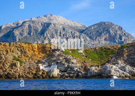 Kleine weiße Kapelle unter Felsen am Meer, Telendos, Kalymnos, Griechenland Stockfoto