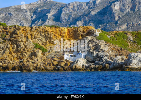 Kleine weiße Kapelle unter Felsen am Meer, Telendos, Kalymnos, Griechenland Stockfoto