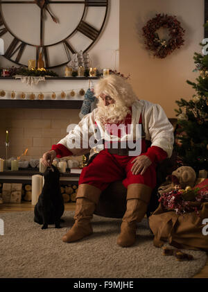 Santa Claus zu Hause mit seiner Katze Stockfoto