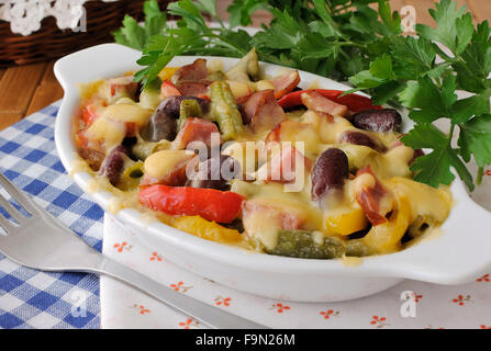 Bohnen mit Schinken und Gemüse, überbacken mit Käse auf der Platte Stockfoto