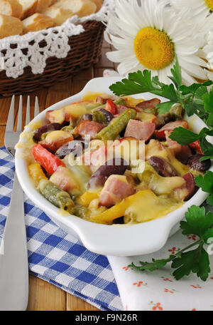 Bohnen mit Schinken und Gemüse, überbacken mit Käse auf der Platte Stockfoto