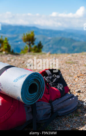 Closeup rot Rucksack mit Isomatte legt auf felsigen Boden vor Berg Tajamulco und blauer Himmel mit Wolken Stockfoto