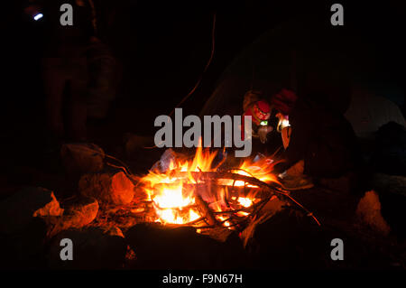 Wanderer versammelten sich rund um ein Lagerfeuer am Abend mit Langzeitbelichtung geschossen Stockfoto