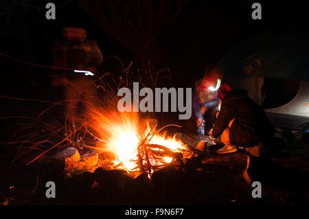 Wanderer versammelten sich rund um ein Lagerfeuer am Abend mit Langzeitbelichtung geschossen Stockfoto